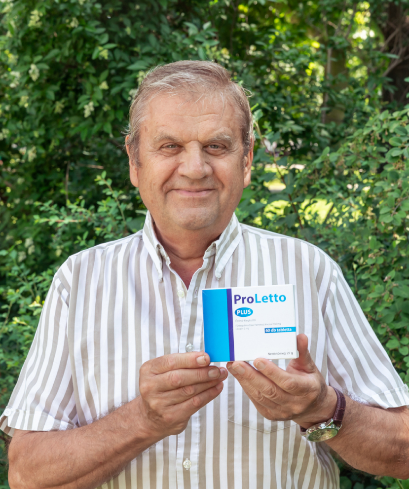 Natural Pharmaceuticals ProLetto® Plus Középkorú férfi szürke pulóverben, bronz emlékmű előtt, szabadtéri portré.
